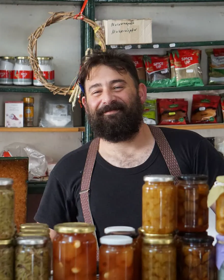 A deli owner smiling behind his counter
